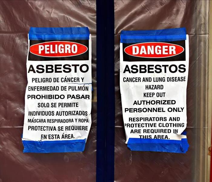 Sign in Spanish and English warning of asbestos danger on a window